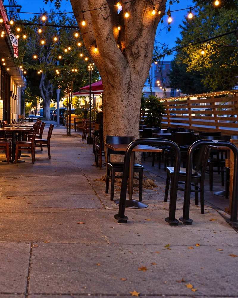 Patio tables beneath a tree strung with lights on Vermont Avenue at dusk